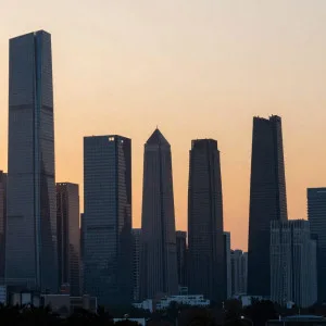 City skyline with tall skyscrapers silhouetted against orange and peach sunset sky during golden hour